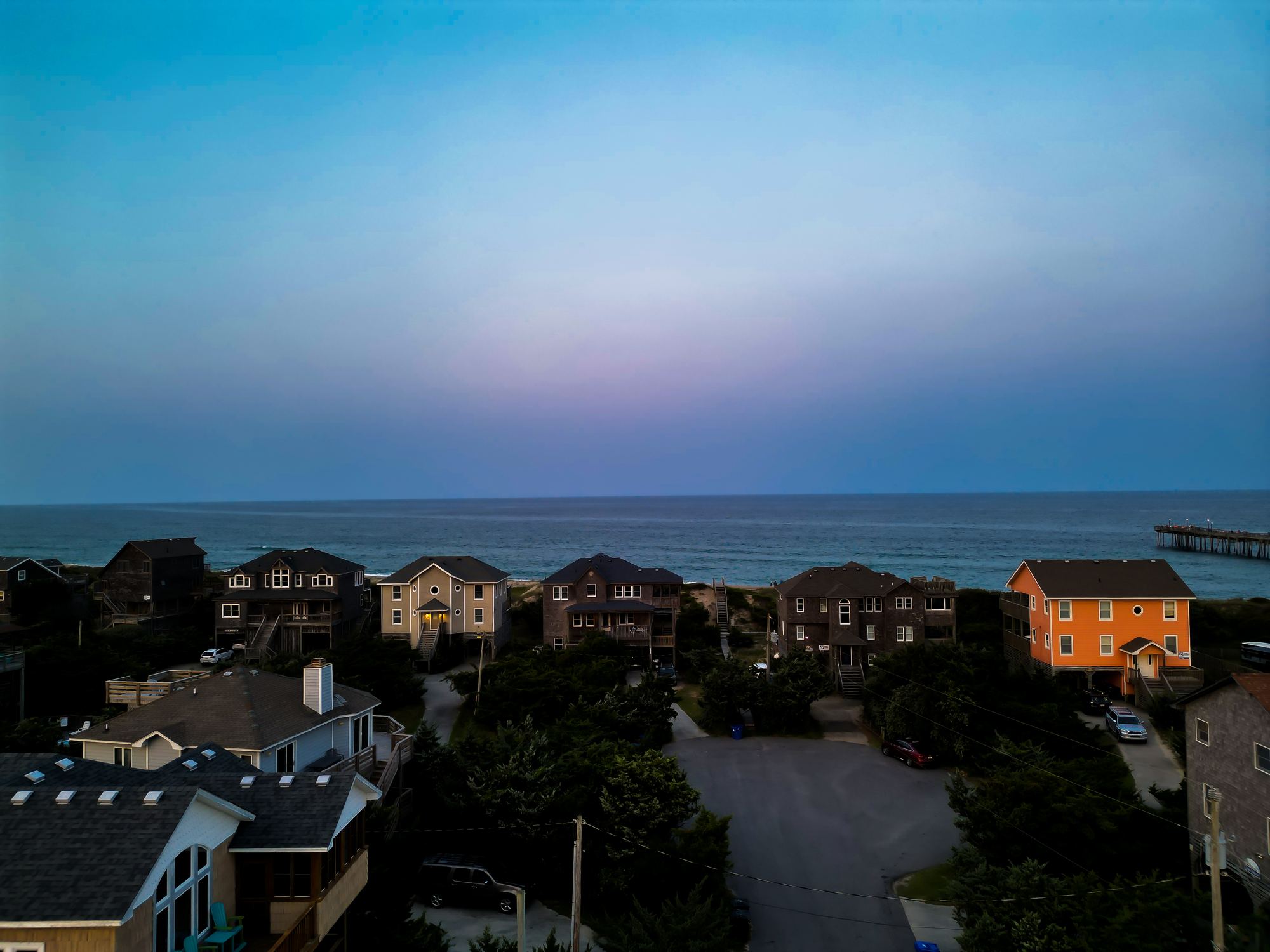 Beach cottages at blue hour with a fishing pier in the distance