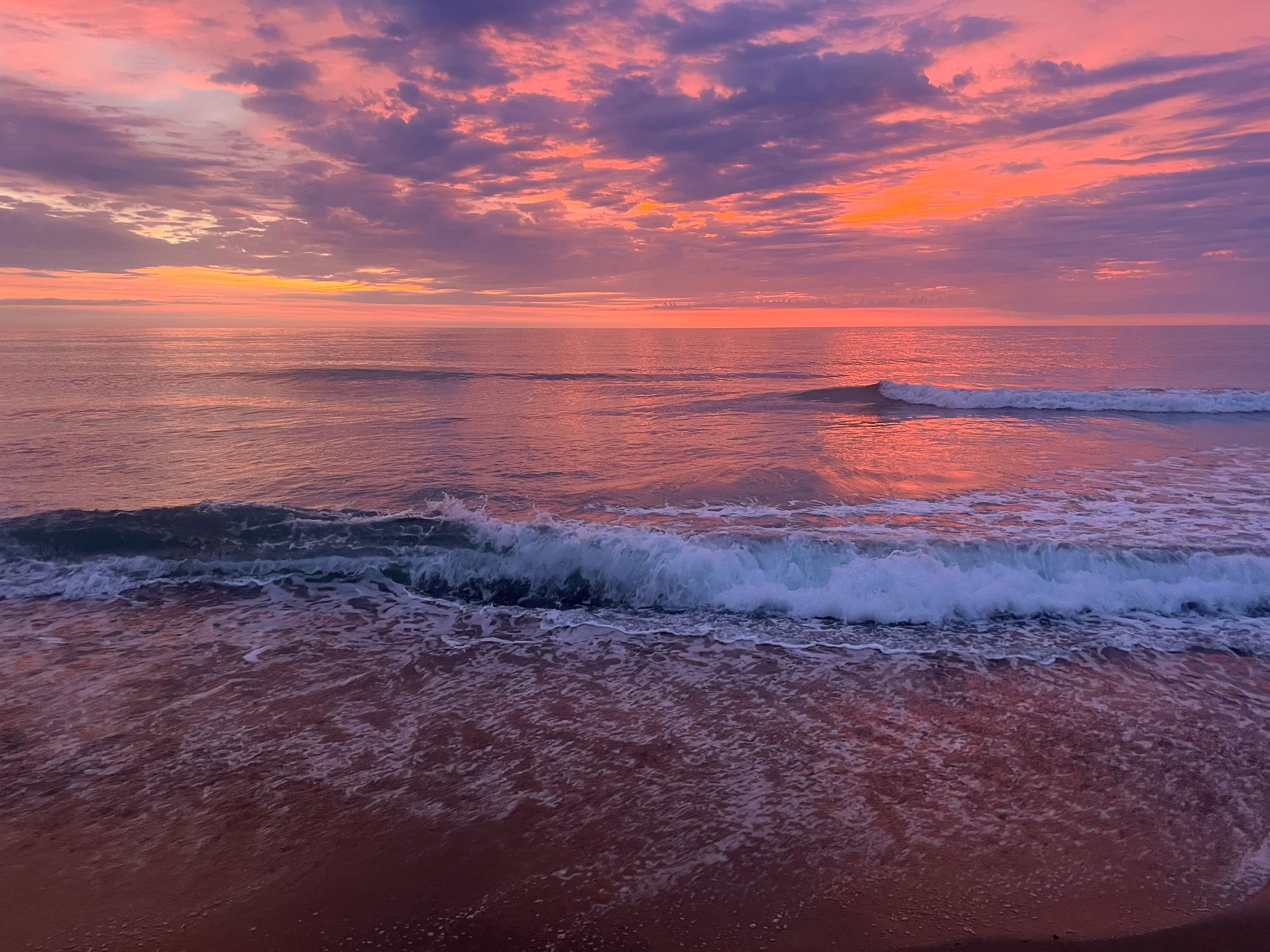 Pink and violet sunrise over breaking Atlantic surf